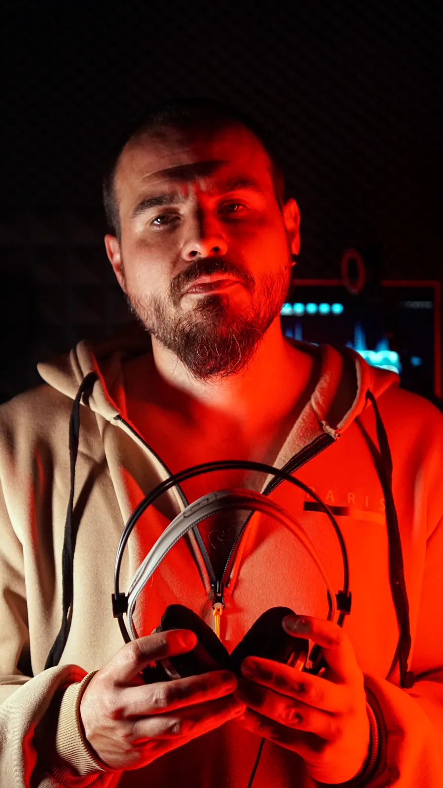 Adri sujetando unos cascos bajo la luz roja del estudio
