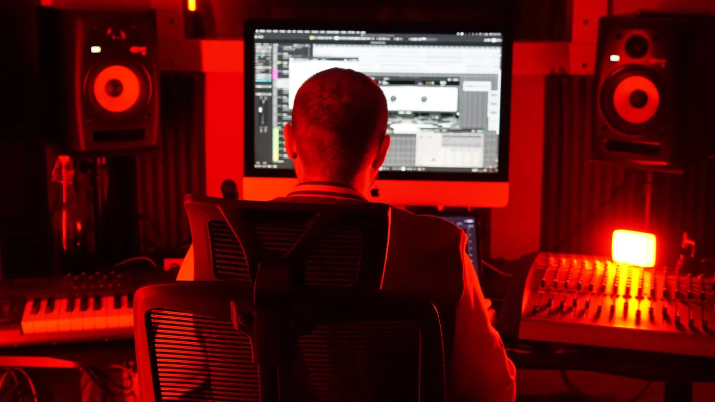 Adri de espaldas frente a los monitores, con la sala en rojo