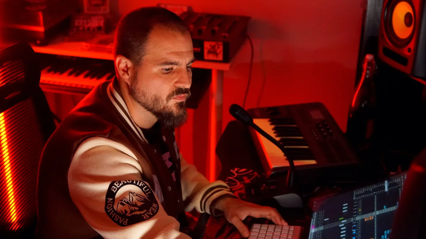 Adri produciendo concentrado en su puesto, con el teclado y los monitores bajo la luz roja